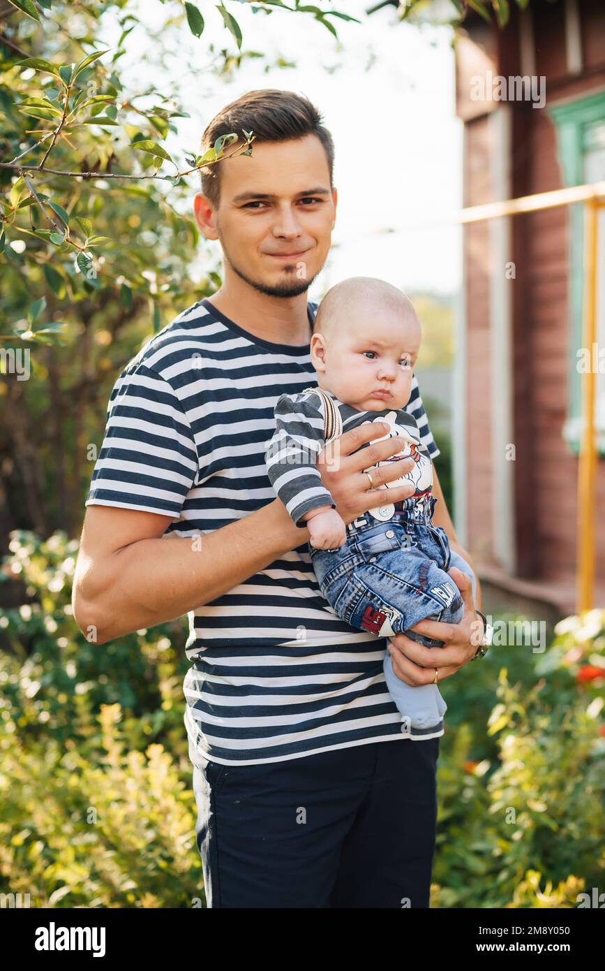 Felice giovane papà caucasico con neonato in mano sorridendo in estate nel Parco Foto Stock