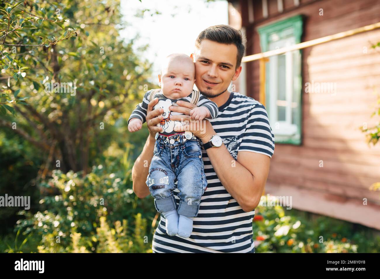 Felice giovane papà caucasico con bambino neonato in mani sorridente in estate Foto Stock