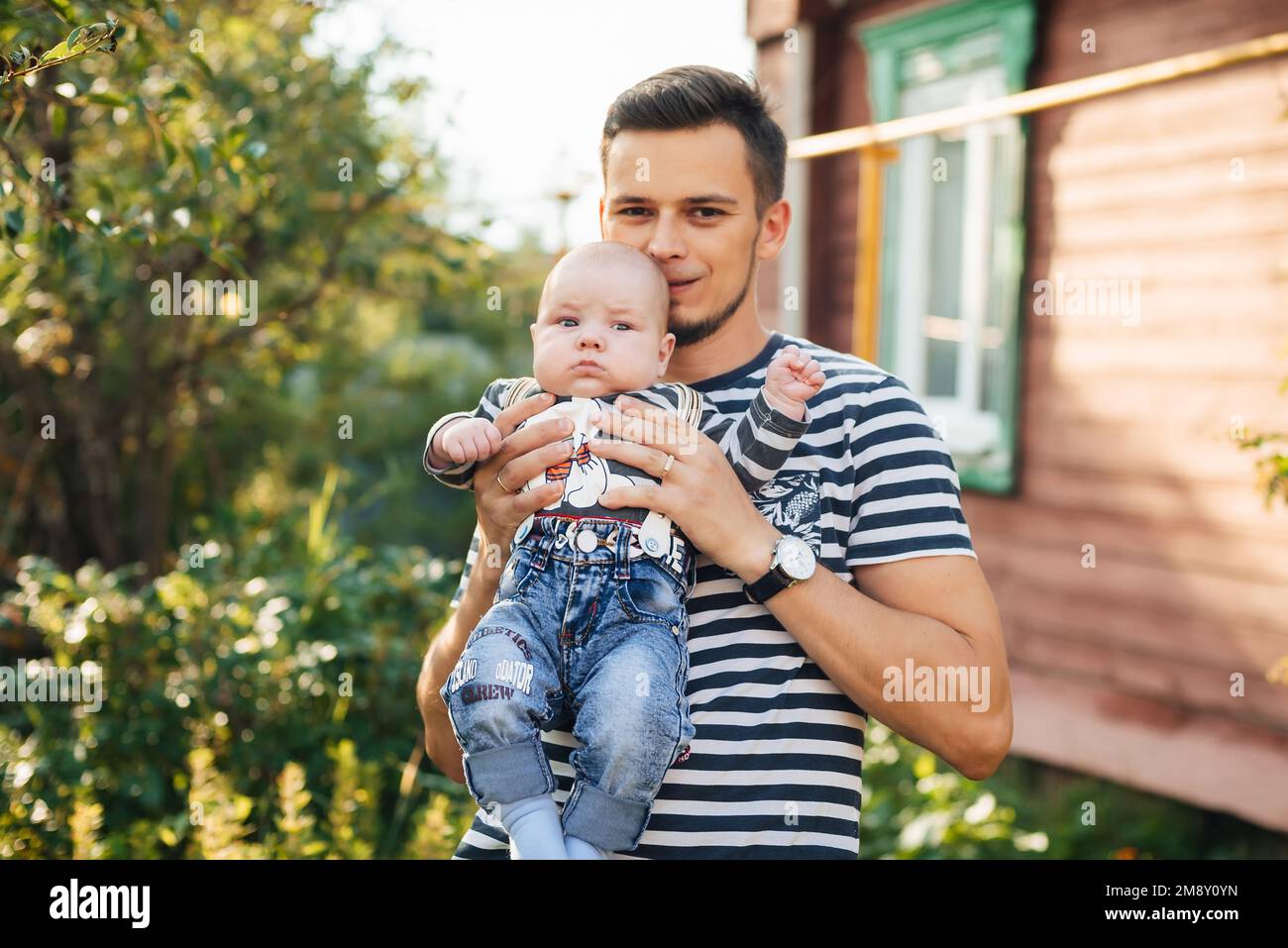 Felice giovane papà caucasico con bambino neonato in mani sorridente in estate Foto Stock