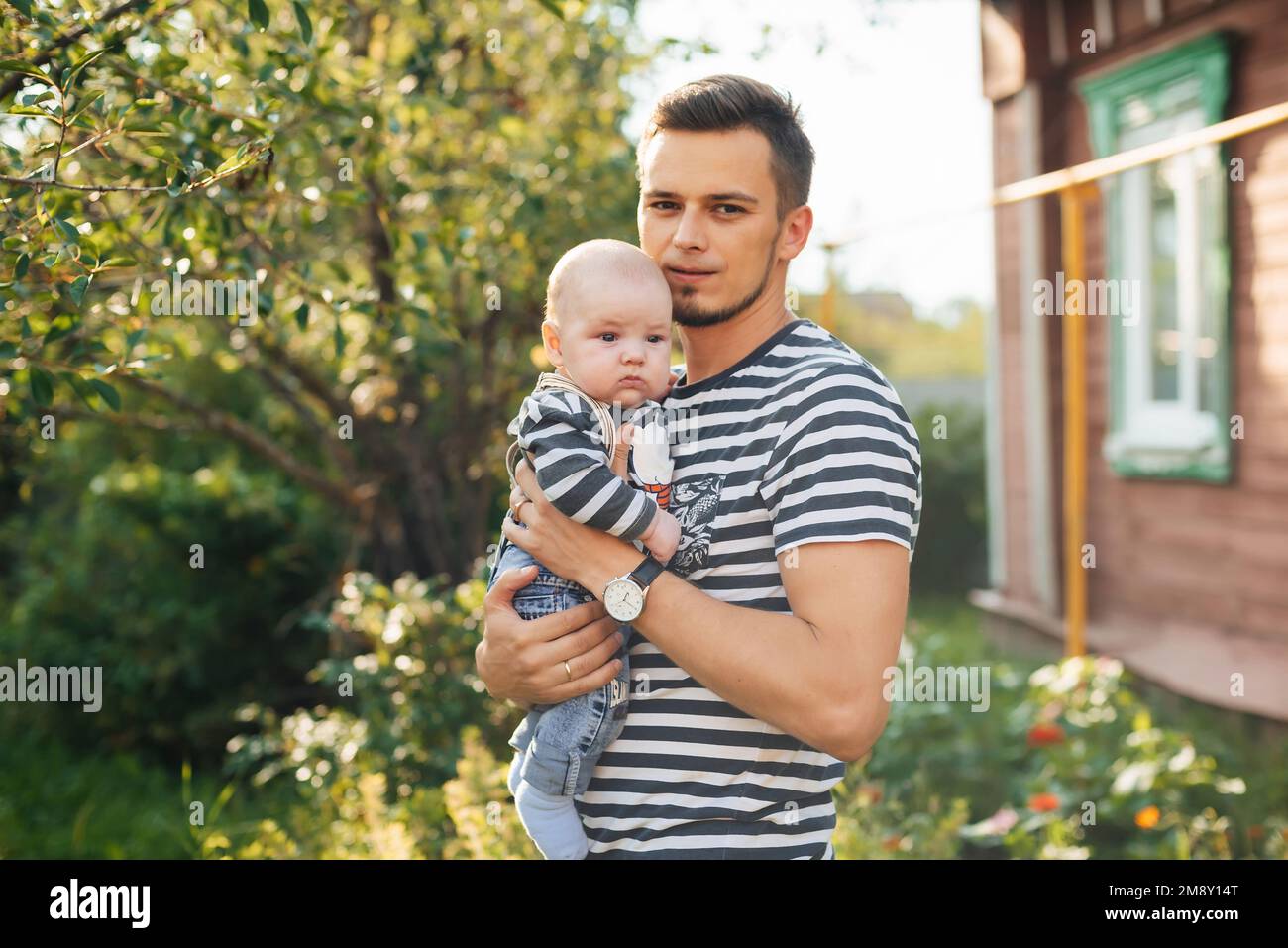 Felice giovane papà caucasico con neonato in mano in estate Foto Stock