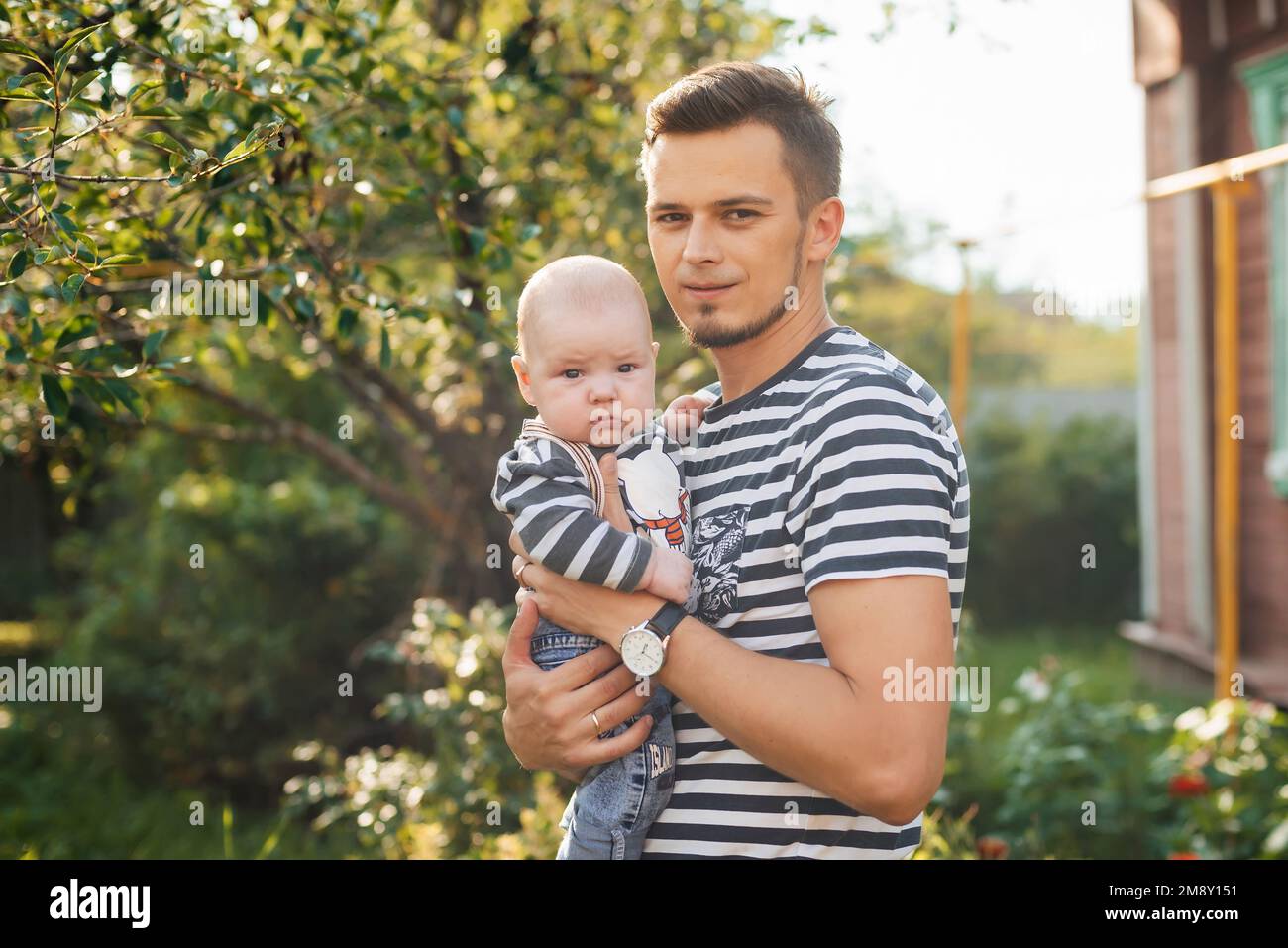 Felice giovane papà caucasico con neonato in mano in estate Foto Stock