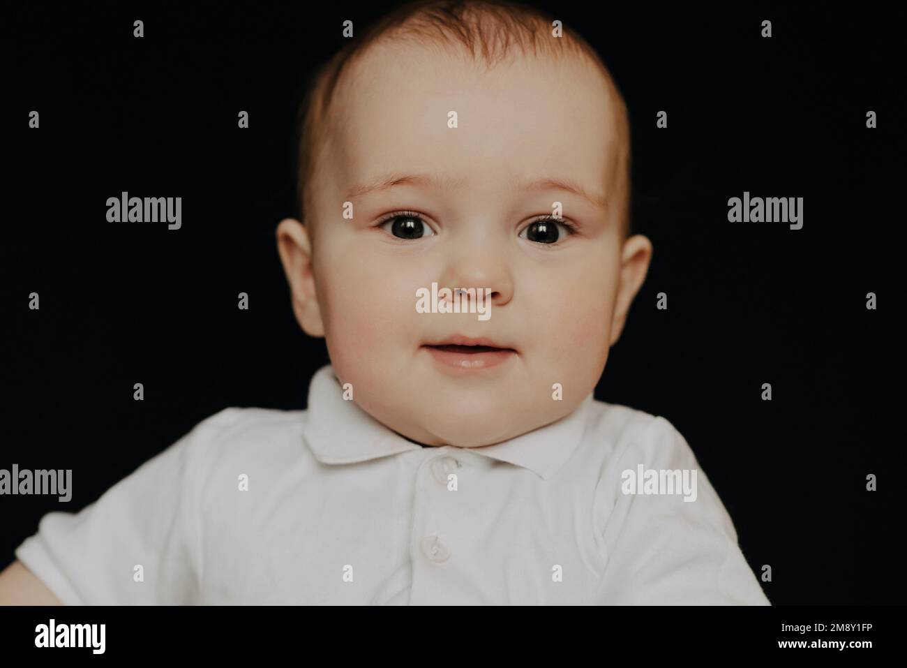 Ritratto di un ragazzino ridente. Bambino caucasico su sfondo nero Foto Stock