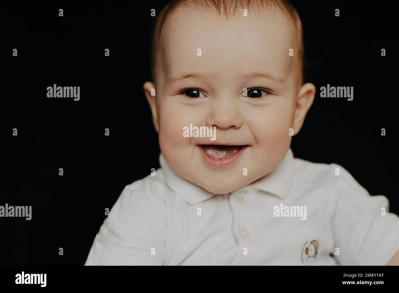 Ritratto di un ragazzino ridente. Bambino caucasico su sfondo nero Foto Stock