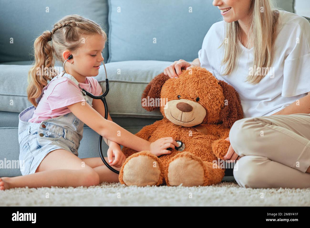 Ha bisogno di un controllo. una bambina e sua madre che gioca medico con un orsacchiotto a casa. Foto Stock