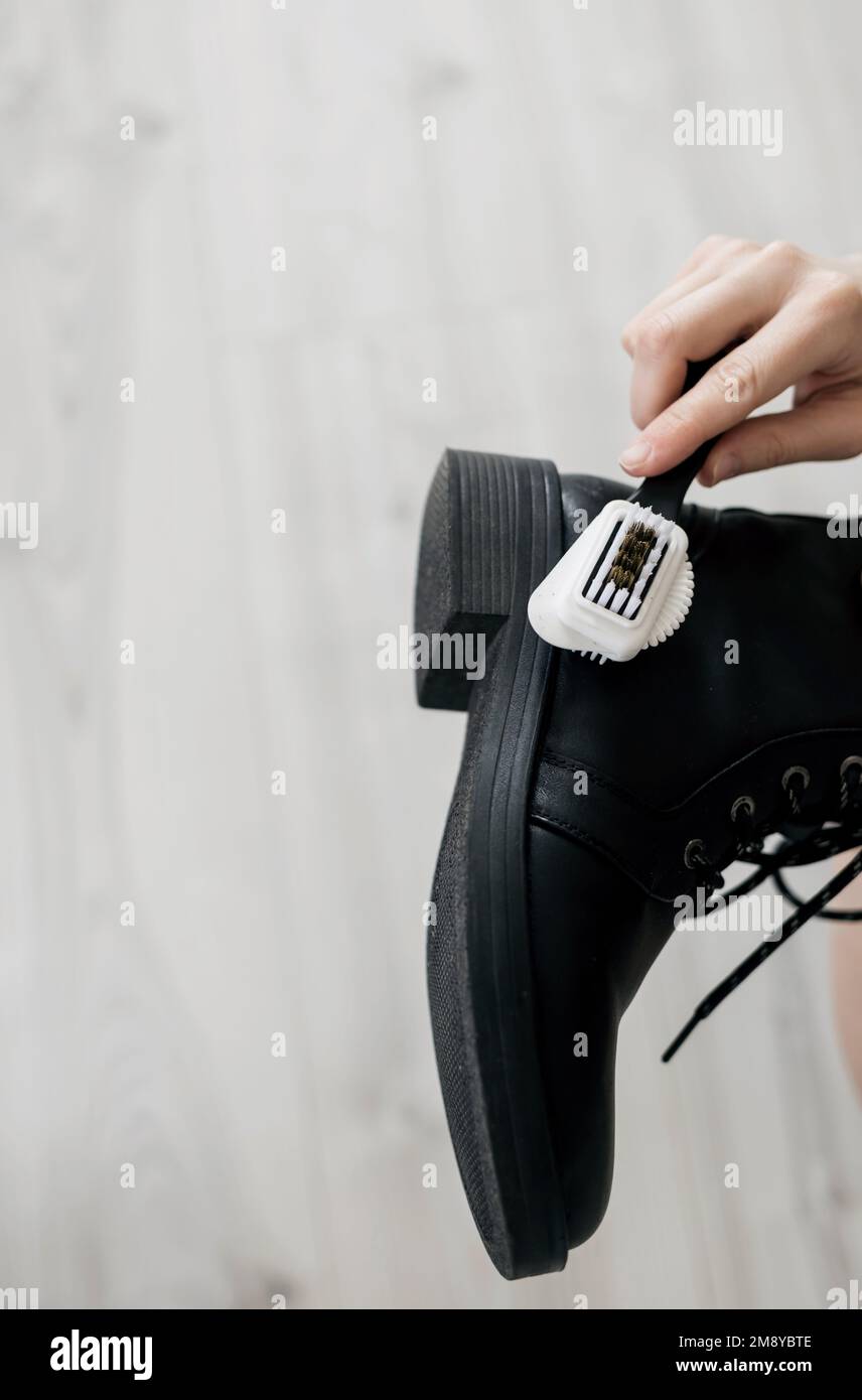 Scarpe di pulizia. Donna che pulisce eleganti scarpe nere Foto Stock