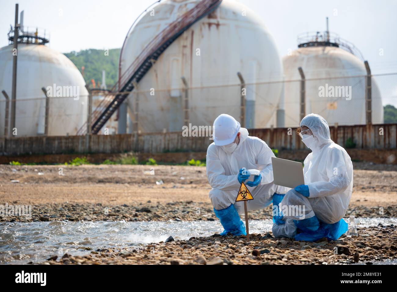 Il biologo indossa tuta protettiva e maschera raccoglie campioni di acque reflue provenienti dall'industria Foto Stock