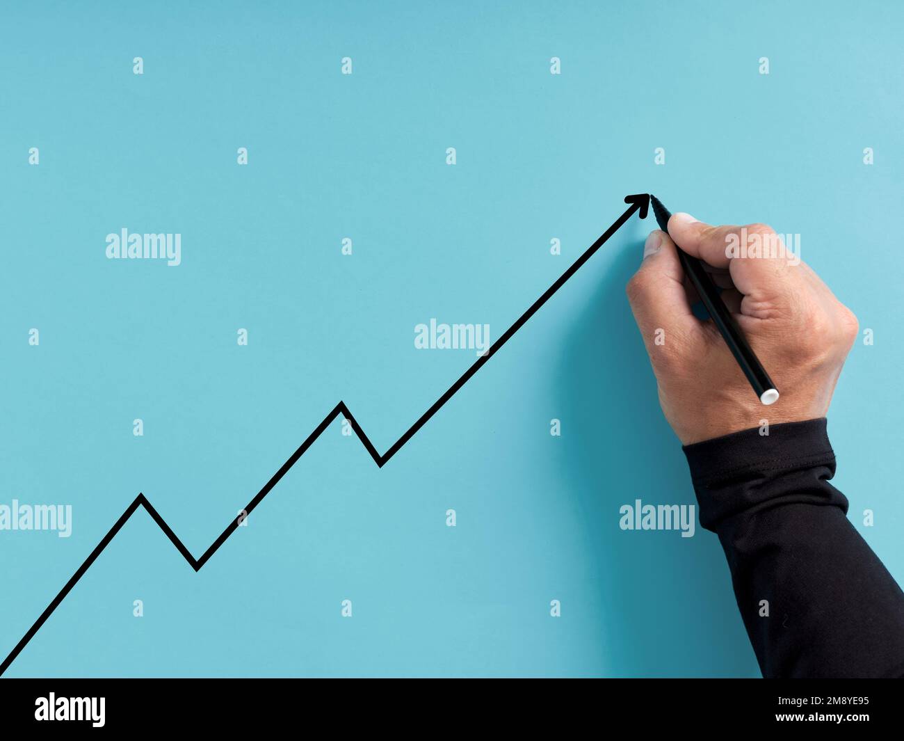 Concetto di crescita e sviluppo economico o commerciale. La mano disegna una linea ascendente su sfondo blu. Foto Stock