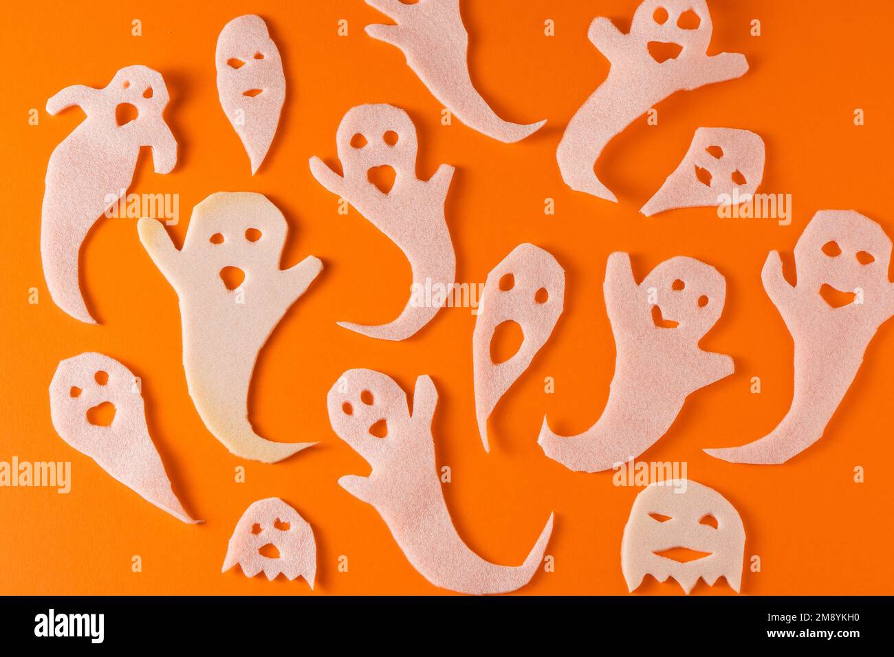 Fantasmi bianchi bambini di mestiere per Halloween. Immagine fantasma su sfondo arancione vista dall'alto. Un giocattolo spaventoso e divertente mostro. Fumetto Creepy Whisper. Fai-da-te fatto a mano. Impostare i caratteri boo Spooky Halloween fantasma Foto Stock