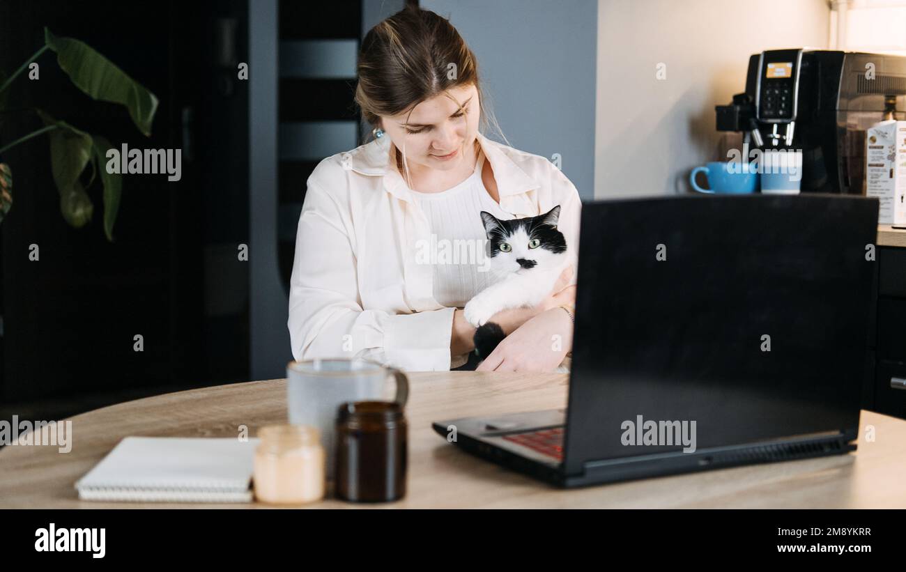 Servizi telemedicina veterinaria, servizi veterinari online per la cura virtuale degli animali domestici. Giovane donna con gatto e utilizzando il computer portatile per videochiamare riunione e. Foto Stock