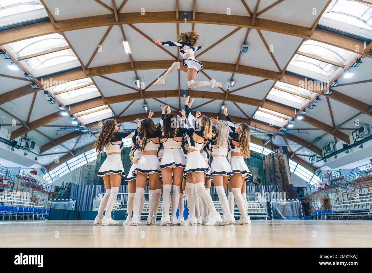 Colpo pieno di una squadra cheerleading hrowin uno dei loro compagni di squadra in alto in aria. Concetto sportivo. Foto di alta qualità Foto Stock