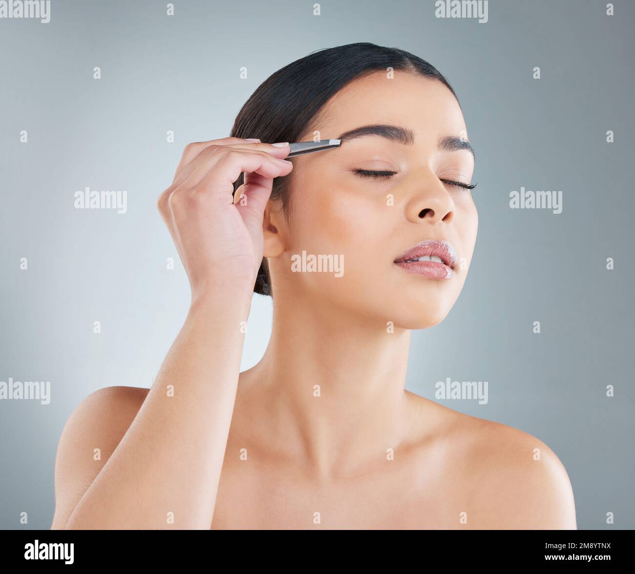 Mantenendo le sopracciglia pulite e ordinate. una giovane donna attraente che posa in studio su uno sfondo grigio. Foto Stock