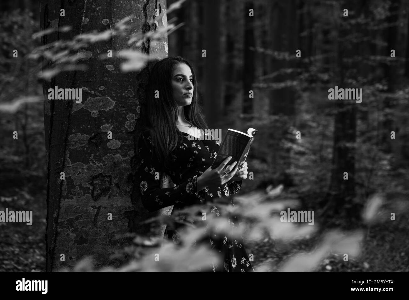 Una donna caucasica in possesso di un libro e in piedi nella foresta Foto Stock