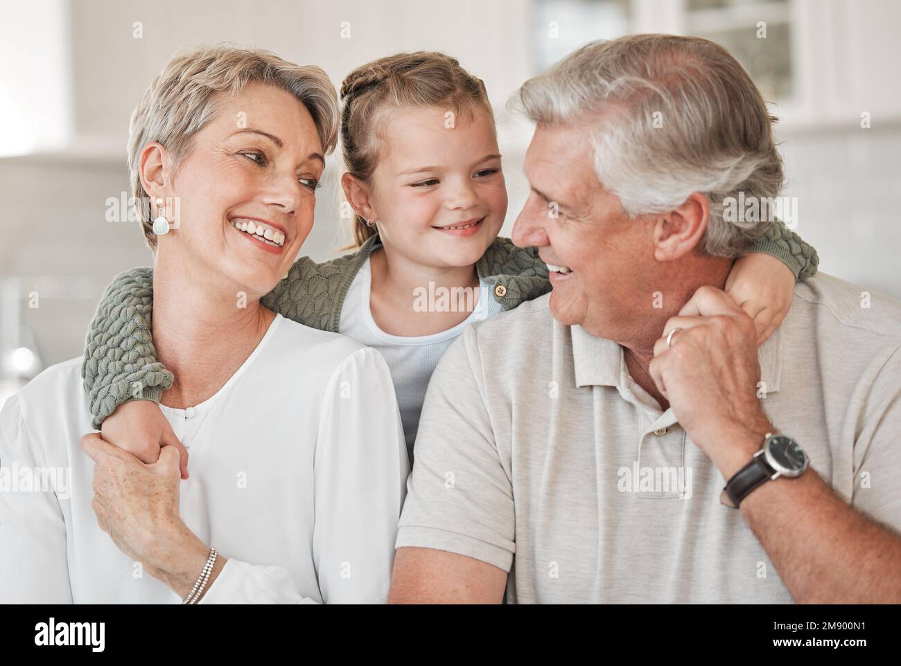 I grandkids li manterranno giovani. una coppia felice e la loro nipote si rilassano sul divano di casa. Foto Stock