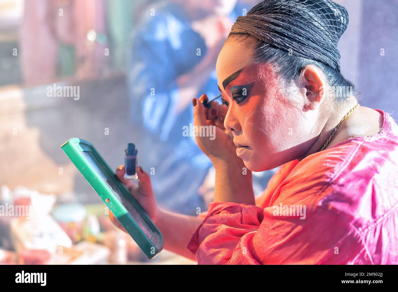 L'attore dell'opera cinese cosmetica fa il viso da dipingere prima di esibirsi nella fase posteriore del teatro Foto Stock