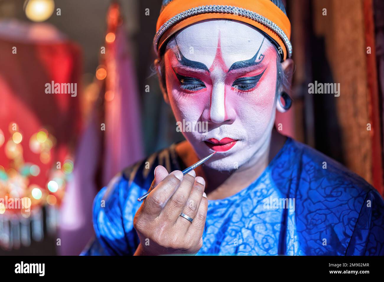 L'attore dell'opera cinese cosmetica fa il viso da dipingere prima di esibirsi nella fase posteriore del teatro Foto Stock