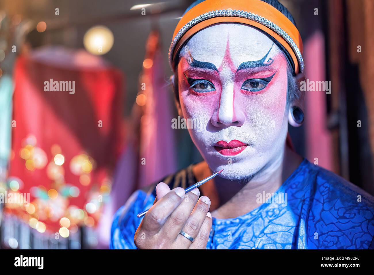 L'attore dell'opera cinese cosmetica fa il viso da dipingere prima di esibirsi nella fase posteriore del teatro Foto Stock