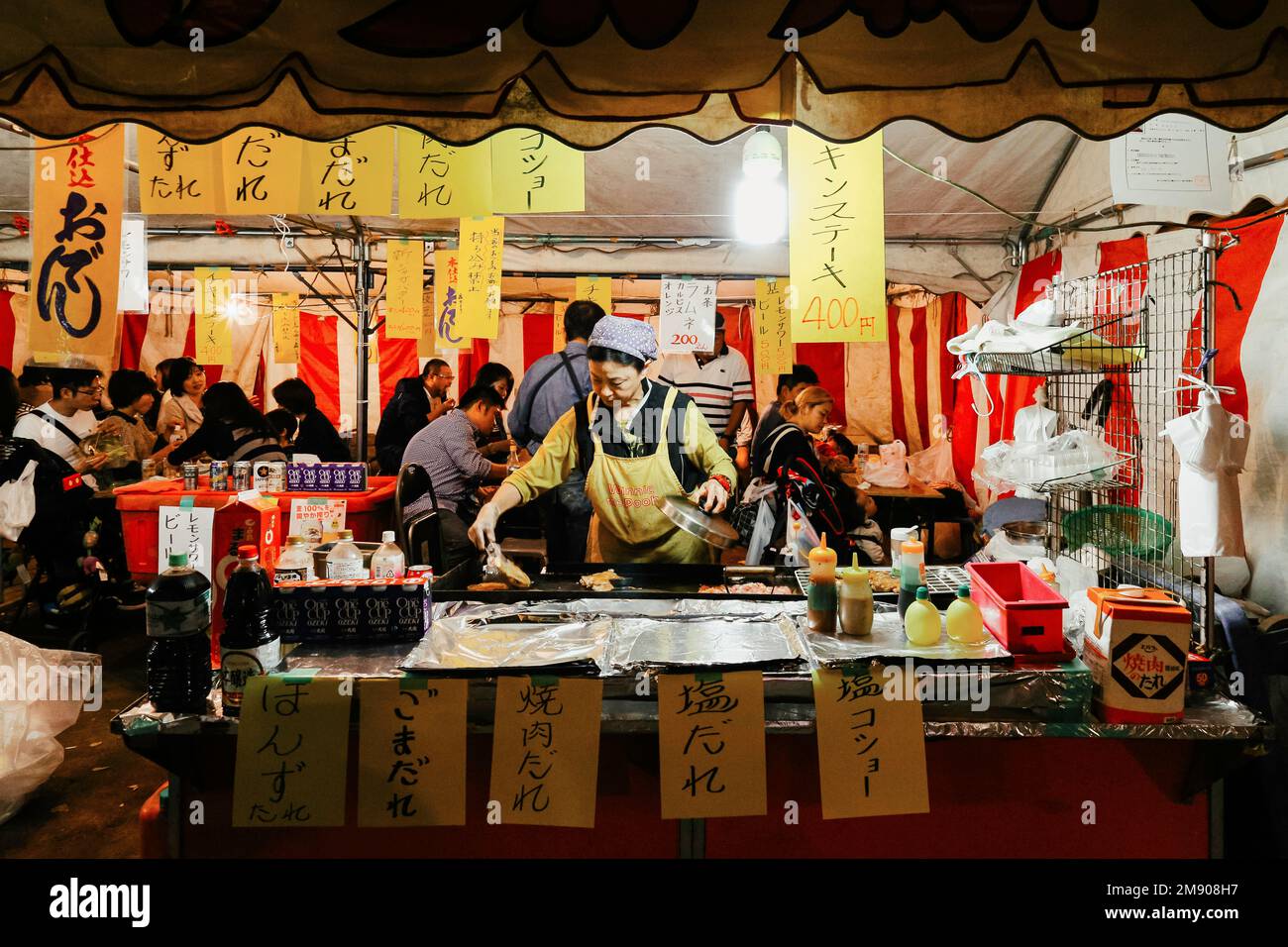 Tokyo, Giappone - 1 Novembre 2022 : cibo di strada Giapponese locale al mercato notturno di Tokyo, Giappone. donna grigliare maiale yakitori e pollo al cibo di strada Foto Stock