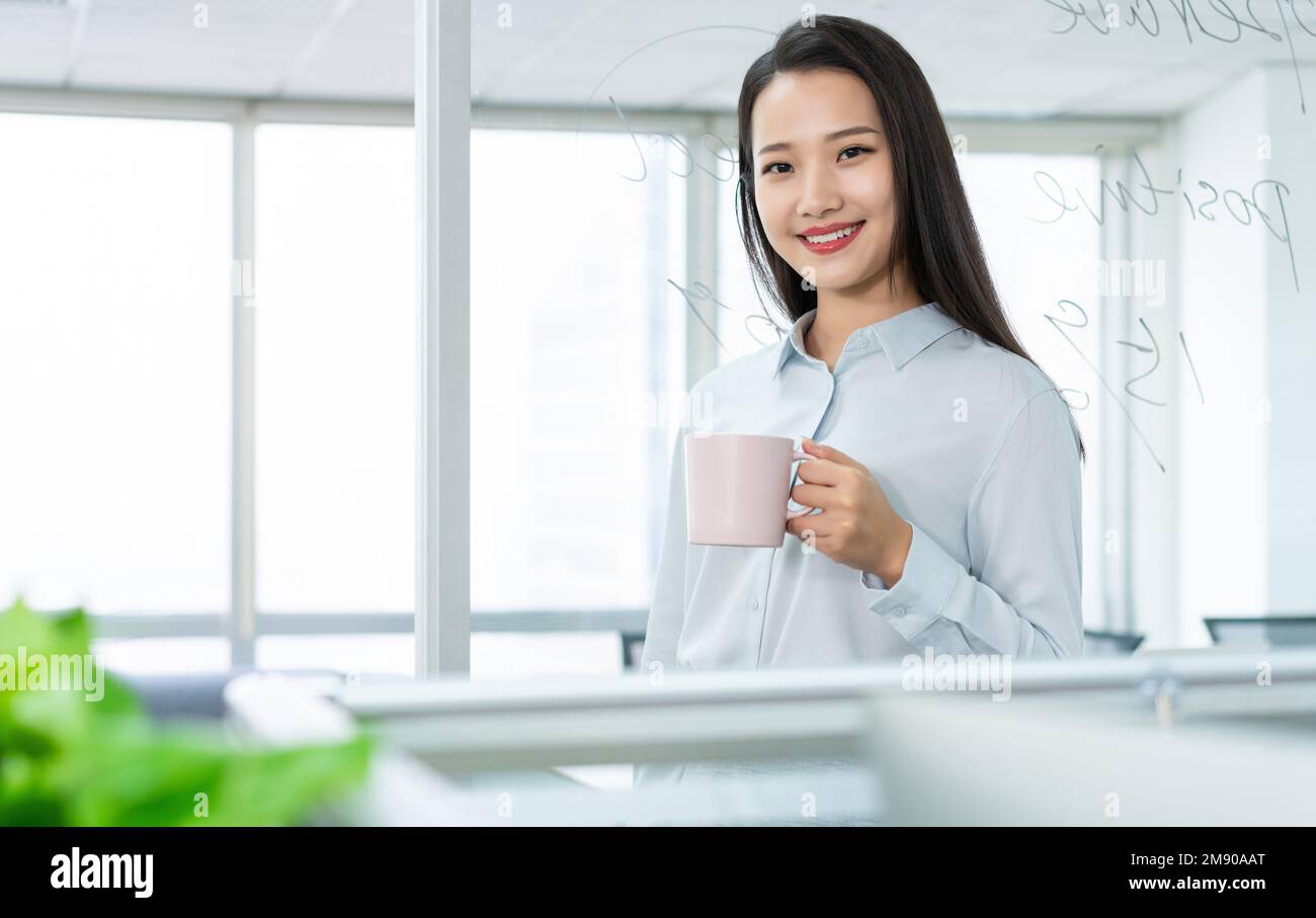 Giovane donna d'affari in ufficio bere caffè Foto Stock