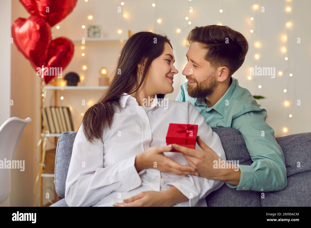 Felice, bello, giovane dà regalo al suo amante attraente il giorno di San Valentino, il compleanno, la festa. Foto Stock