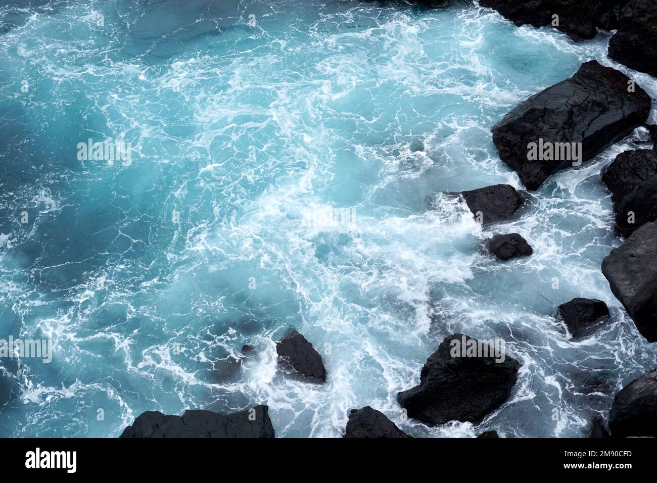 Il potere del mare - le onde si schiantano contro le rocce scure Foto Stock