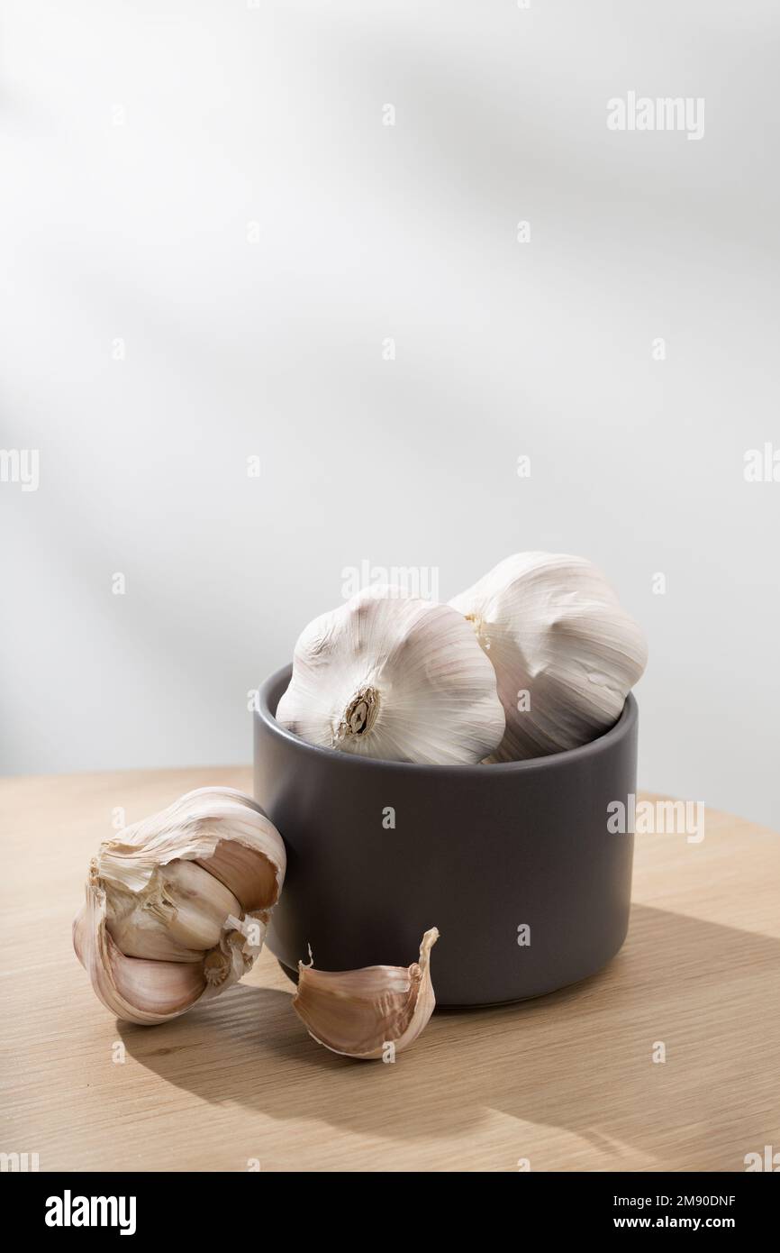 Aglio in ciotola grigia su tavolo di legno Foto Stock