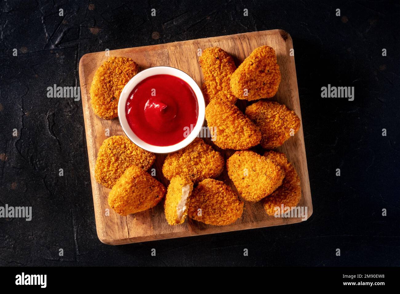 Pepite di pollo su sfondo nero, sparato piatto sopra la testa. Un antipasto croccante in un ristorante, un piatto fast food Foto Stock