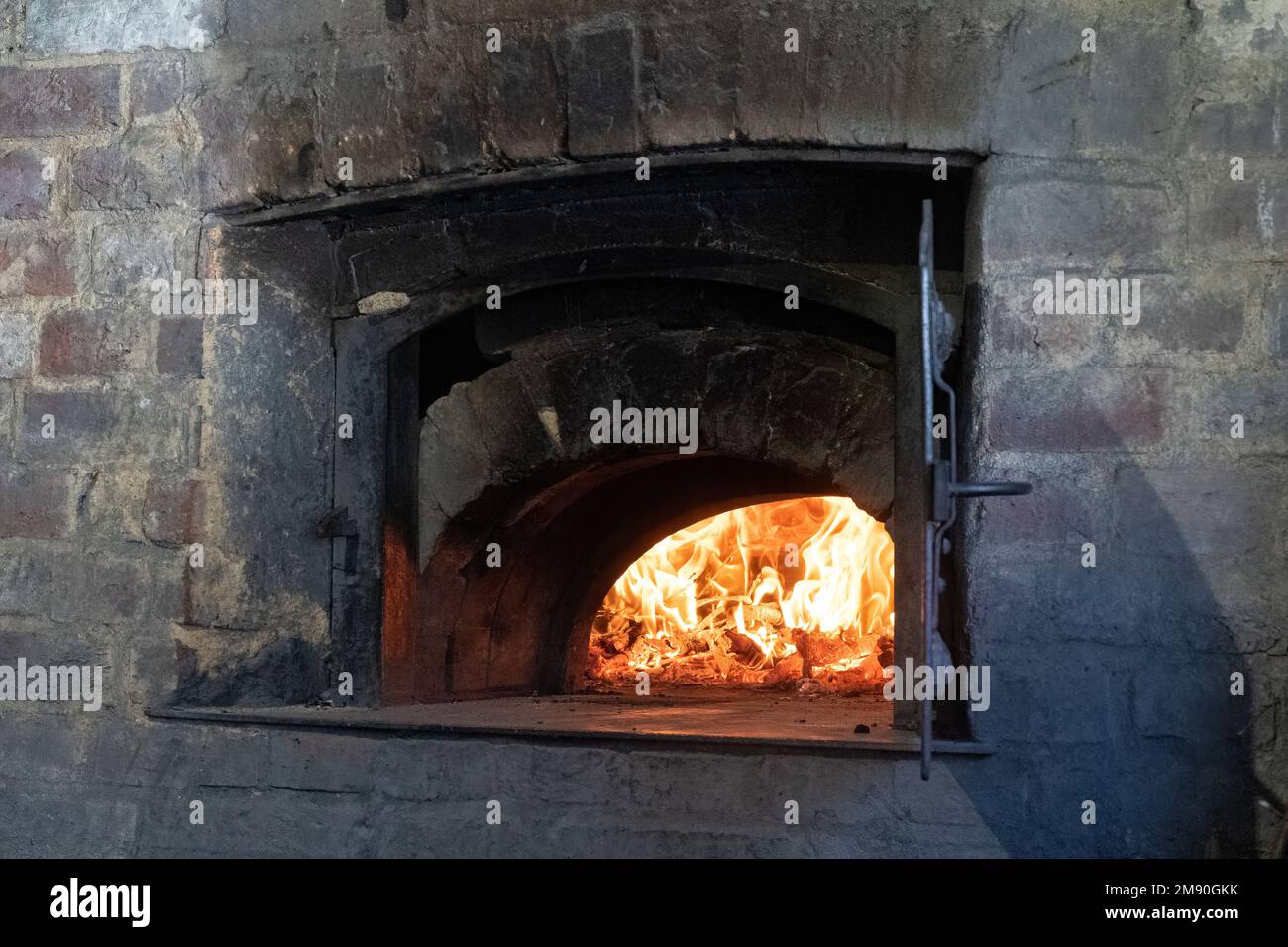 Vecchio forno del pane in uso con fiamme di fuoco, 17th ° secolo il casello del Weald e Downland Living History Museum, West Sussex, Inghilterra, Regno Unito Foto Stock