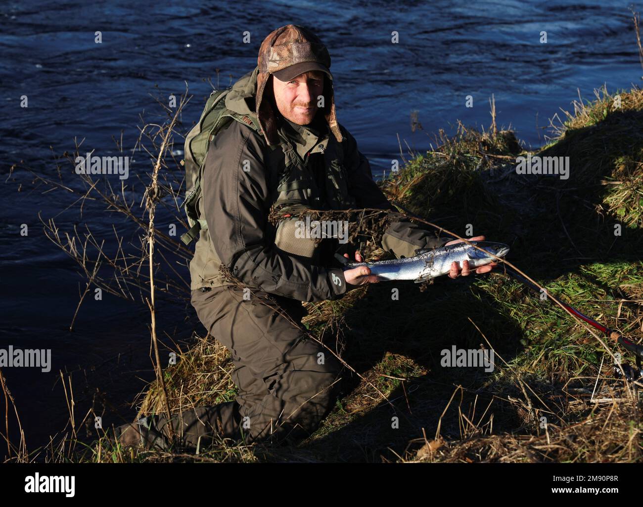 Un pescatore restituisce un kelt dalla banca il giorno di apertura della stagione di pesca del salmone sul fiume Tay a Meikleour pescing, Scozia, Gran Bretagna, 16 gennaio 2023. REUTERS/Russell Cheyne Foto Stock