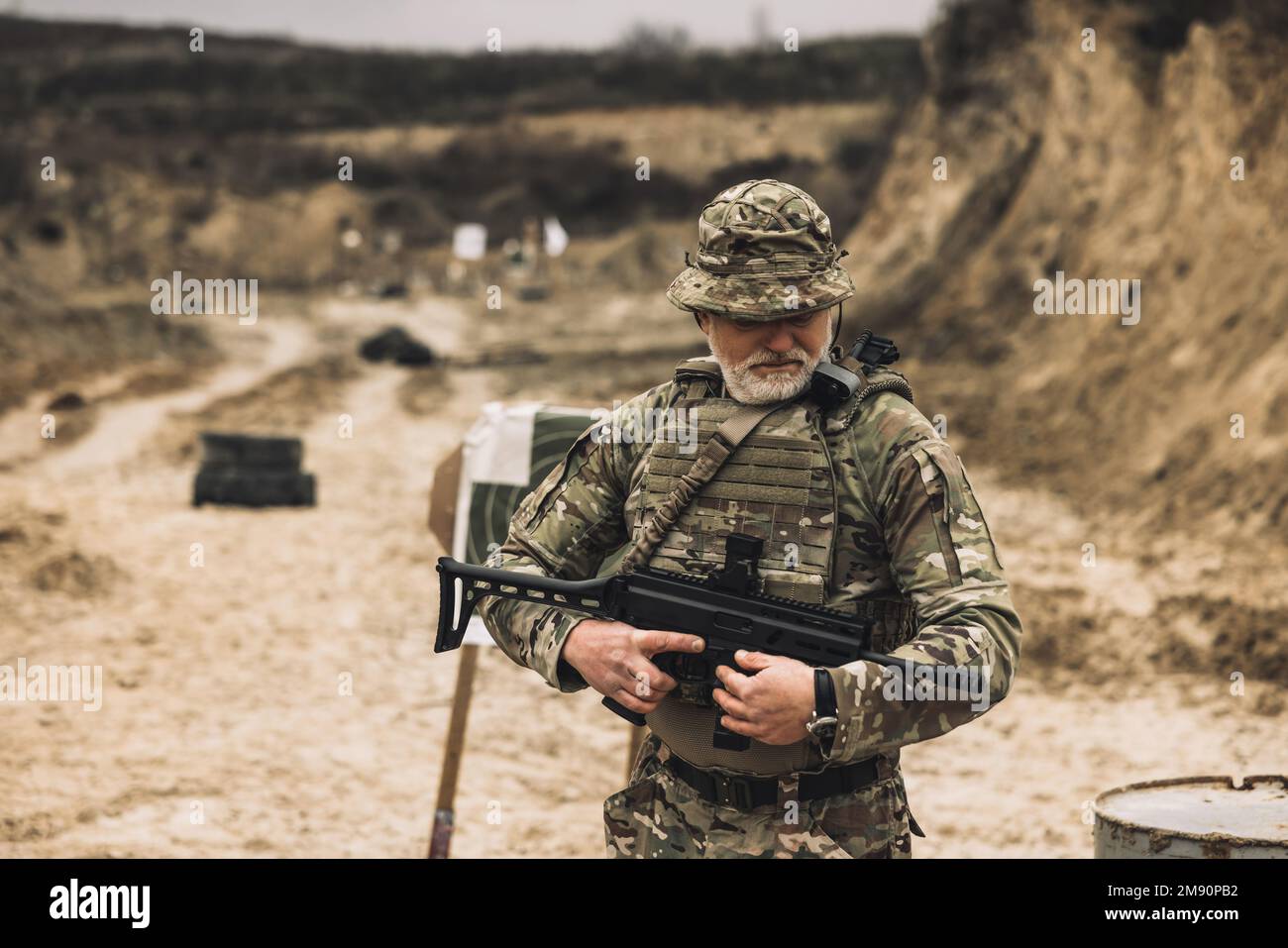 Soldato maturo con un fucile in mano su un campo di tiro Foto Stock