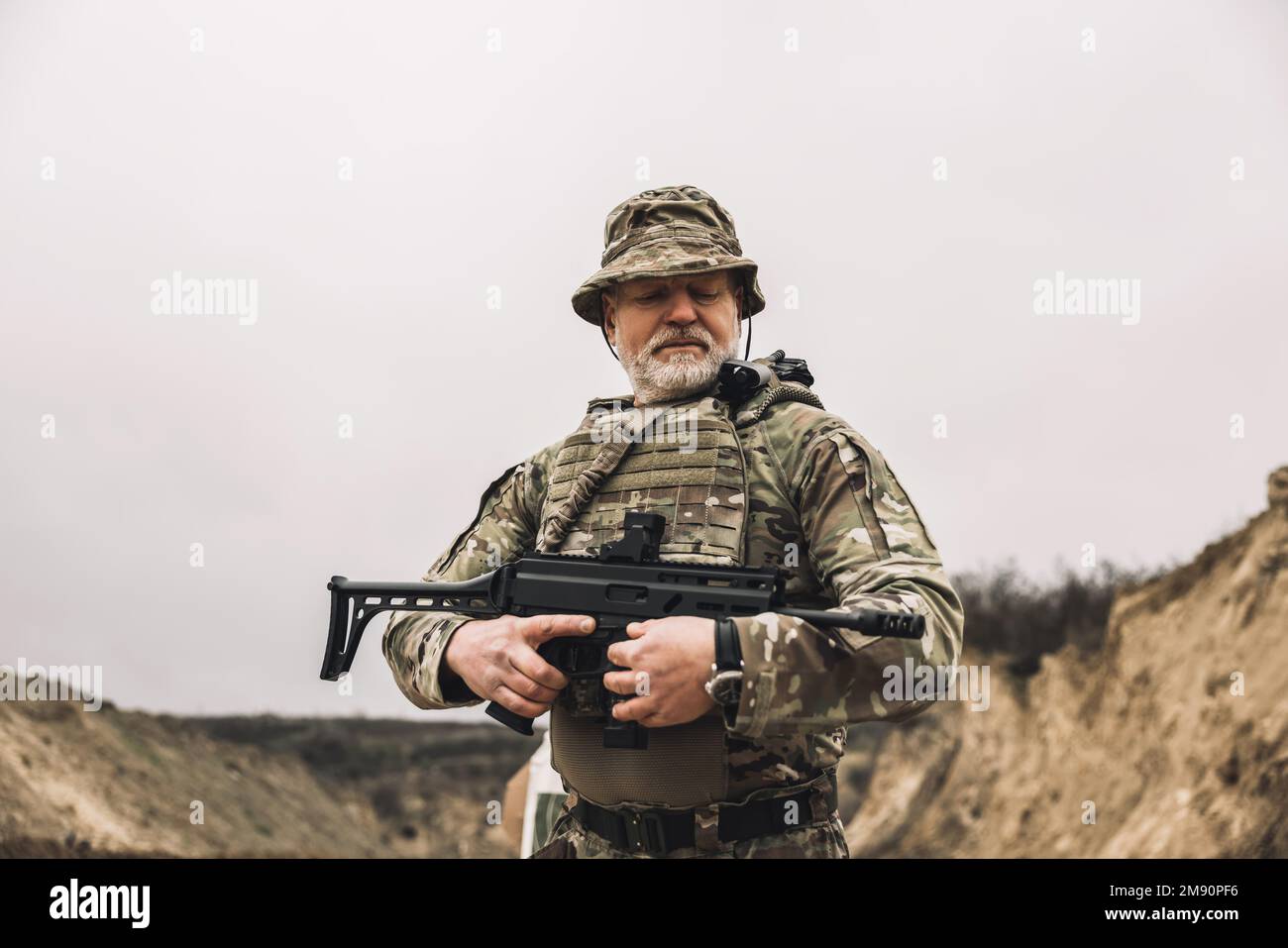 Soldato maturo con un fucile in mano su un campo di tiro Foto Stock