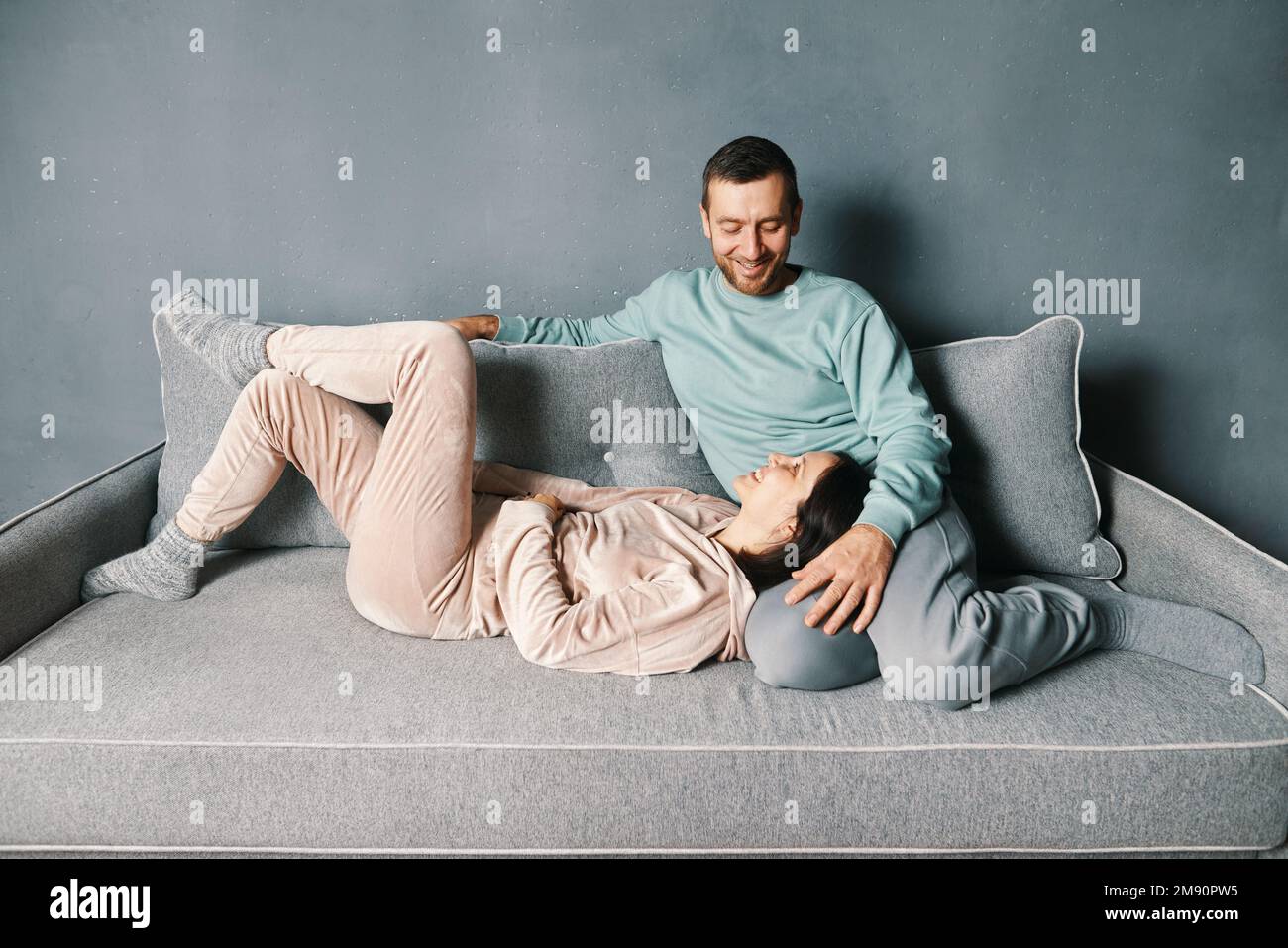 Giovane coppia felice che si rilassa sul divano trascorrendo il proprio tempo insieme a casa. Relazione, amore, concetto di persone Foto Stock