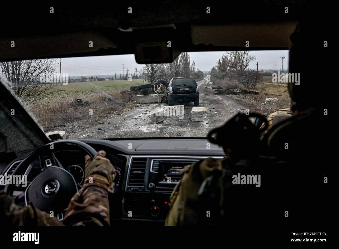 Non esclusiva: ZALIZNYCHNE, UCRAINA - 14 GENNAIO 2023 - i militari seguono un'auto lungo una strada danneggiata, villaggio di Zaliznychne, Zaporizhzhzhia Regione, sud Foto Stock