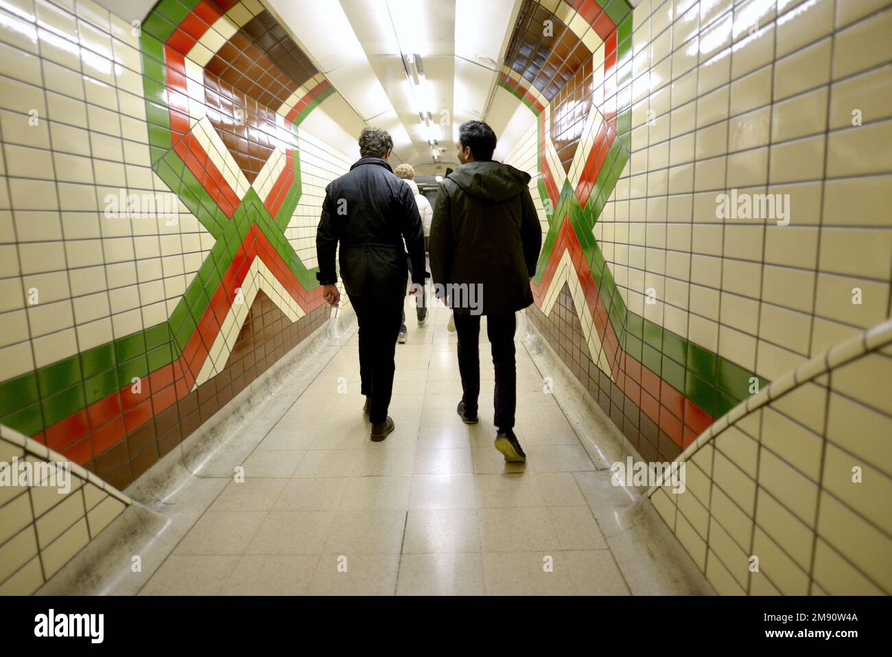 Londra, Inghilterra, Regno Unito. Due uomini che camminano attraverso un tunnel in una stazione sulla Bakerloo Undergournd Line Foto Stock