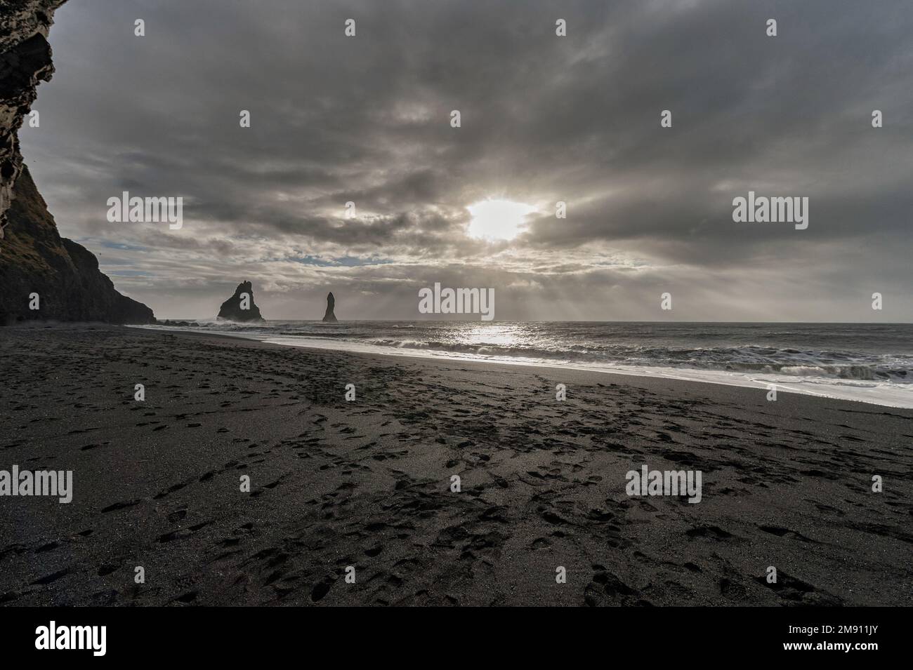 Spiaggia di sabbia nera Reynisfjara in Islanda. Rocce in acqua. Luce solare. Foto Stock