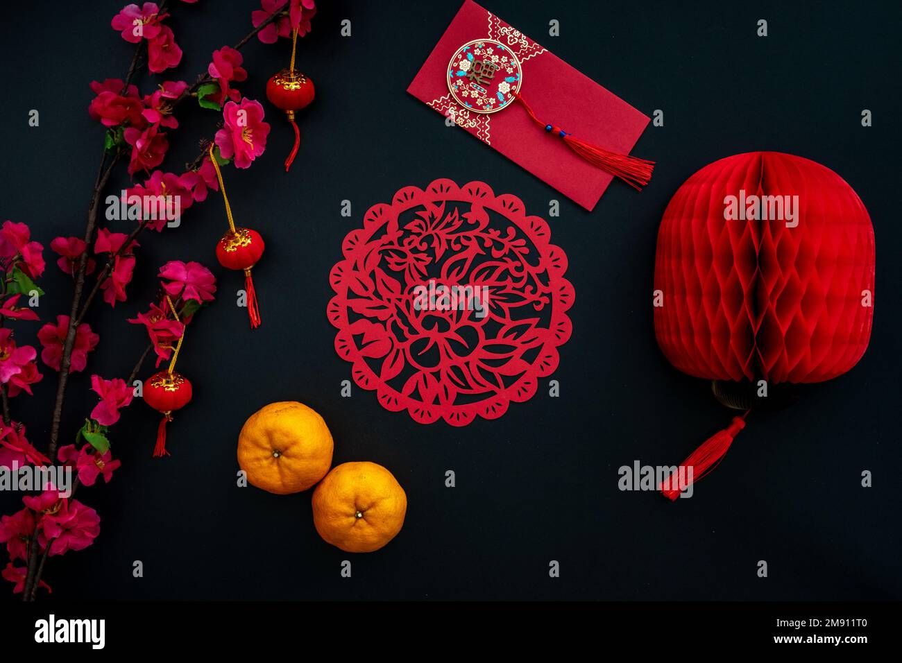 Decorazione cinese lunare di Capodanno su sfondo rosso e nero. Concetto piatto con mandarino, busta rossa, fiore di prugna e decorazione festosa. Foto Stock