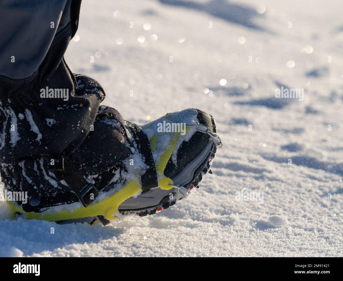 Primo piano di un uomo che si arrampica su una montagna coperta di neve, in scarponi con pattini. Trekking invernale all'aperto Foto Stock