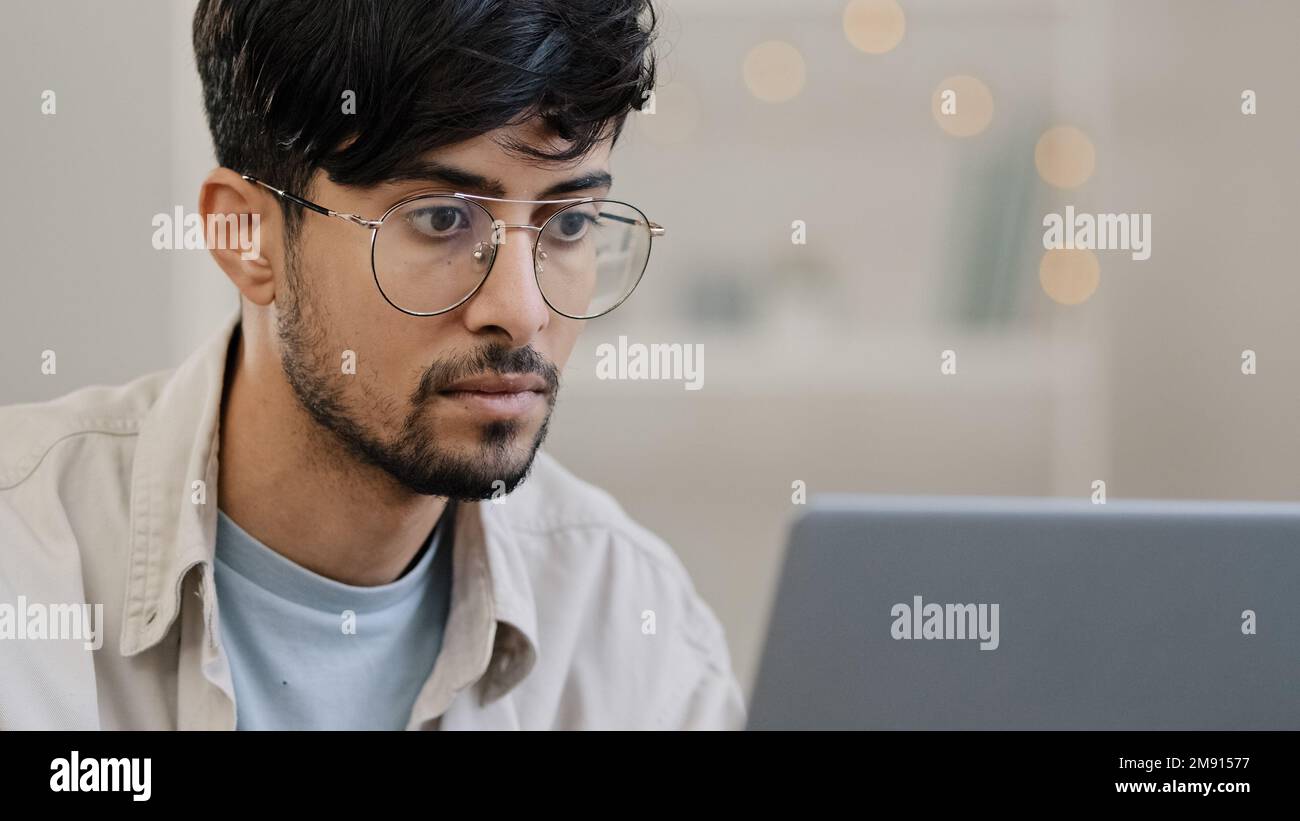 Serio maschio faccia arabo ispanico uomo portatore ragazzo che lavora con il laptop sente lo stress che soffre di mal di testa toglie gli occhiali sfrega gli occhi preoccupati Foto Stock