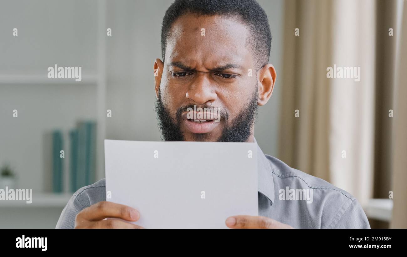 L'uomo del tipo barbuto africano americano infelice ha ricevuto la lettera di lettura difettosa di notizie con la sensibilità di rifiuto della banca sollecitata circa l'avviso di licenziamento. Arrabbiato triste etnico Foto Stock