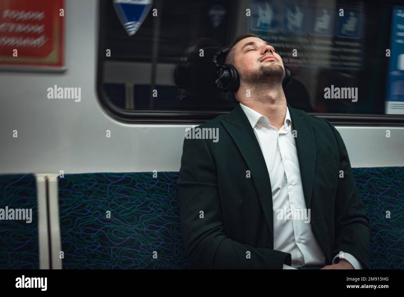 uomo giovane uomo uomo caucasico passeggero una persona positivamente allegro ascolta la musica in cuffie, sognando e andare in metropolitana di trasporto al mattino. Foto Stock