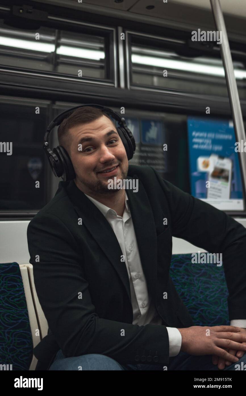 uomo giovane uomo uomo caucasico passeggero una persona positivamente allegro ascolta la musica in cuffie, sorride e andare in metropolitana di trasporto al mattino. co Foto Stock