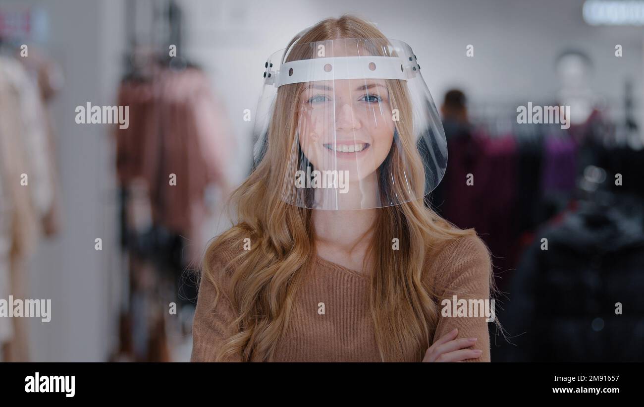 Primo piano sicuro protetto Store Manager ragazza negozio assistente in plastica trasparente maschera scudo ritratto donna sorridente acquirente donna guardando Foto Stock