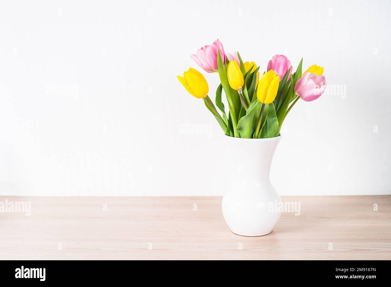 Bouquet di fiori tulipani in vaso bianco di ceramica su sfondo chiaro. Foto Stock