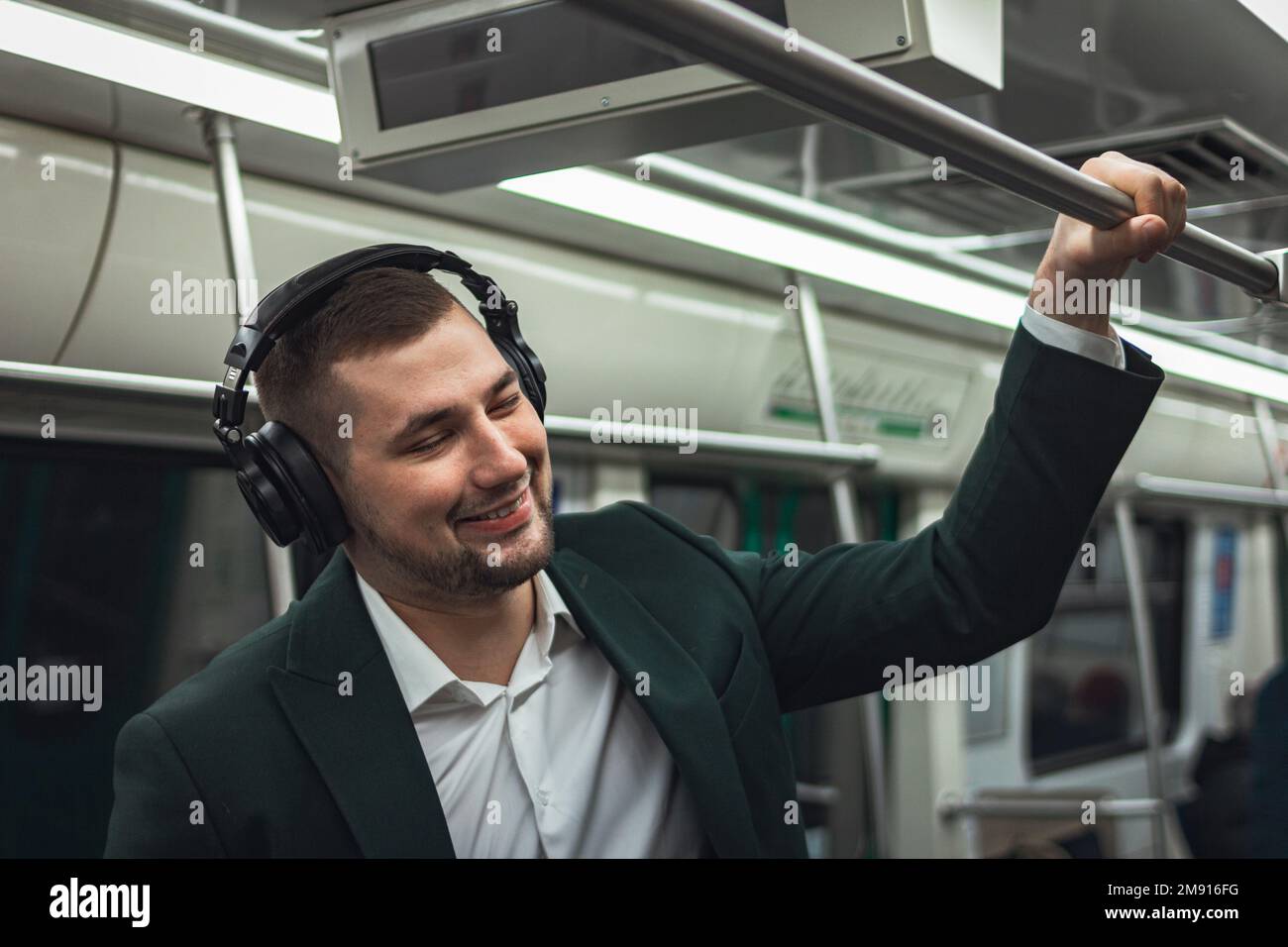 uomo giovane uomo uomo caucasico passeggero una persona positivamente allegro ascolta la musica in cuffie, sorride e andare in metropolitana di trasporto al mattino. abbonamento concettuale alla musica. Foto Stock