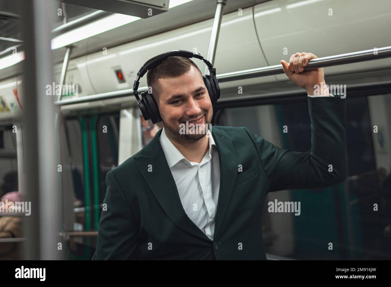 uomo giovane uomo uomo caucasico passeggero una persona positivamente allegro ascolta la musica in cuffie, sorride e andare in metropolitana di trasporto al mattino. abbonamento concettuale alla musica. Foto Stock