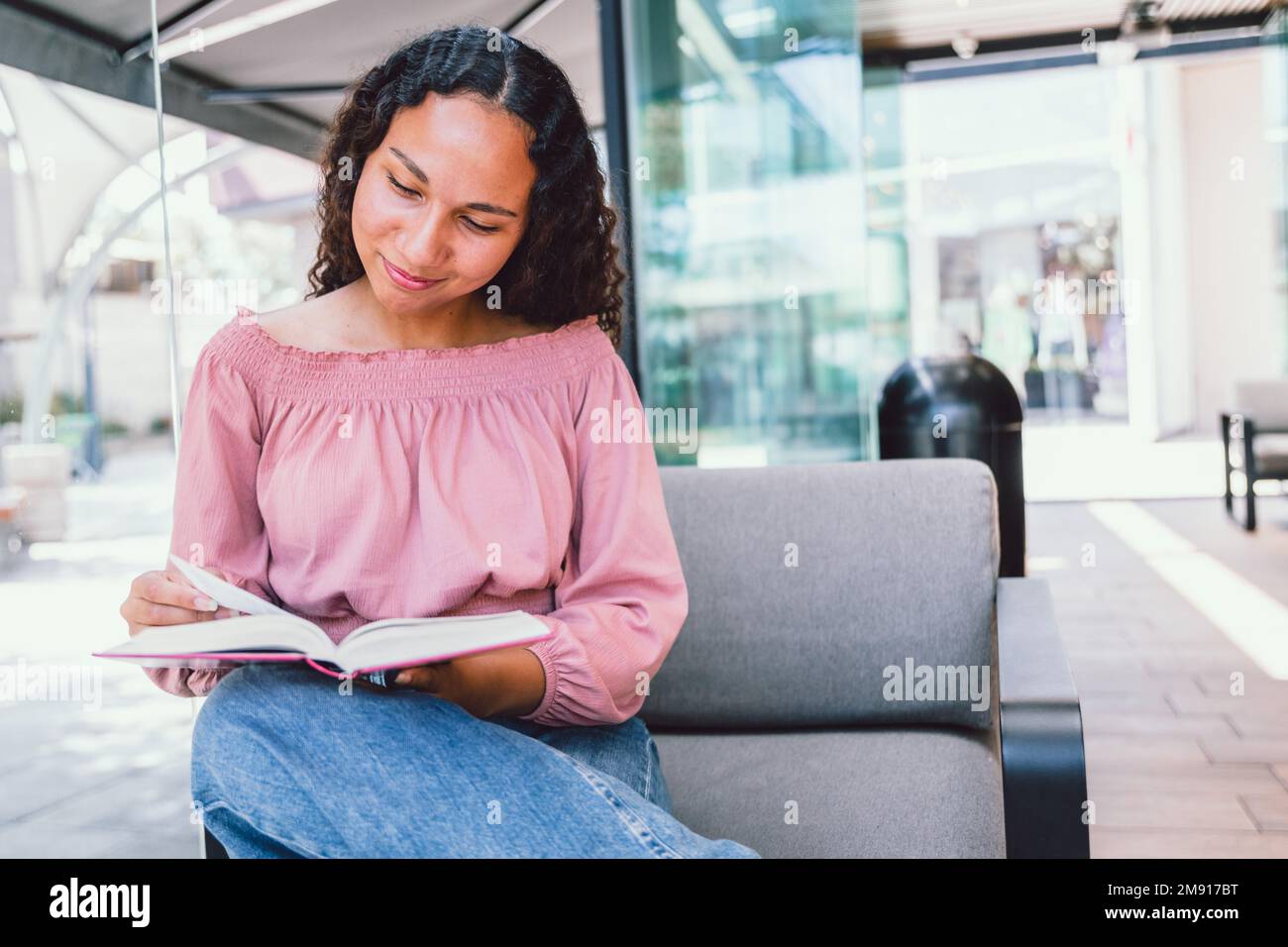 Studentessa universitaria latina seduta e studentessa per un esame al di fuori di un bar. Leggere libri Foto Stock
