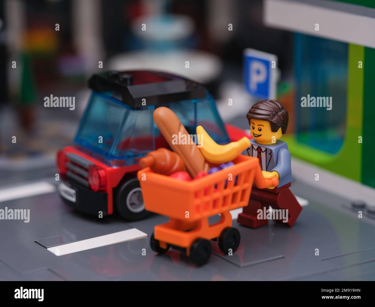 Tambov, Federazione Russa - 14 gennaio 2023 Una figura di affari Lego che spinge un carrello pieno di generi alimentari alla sua auto. Foto Stock