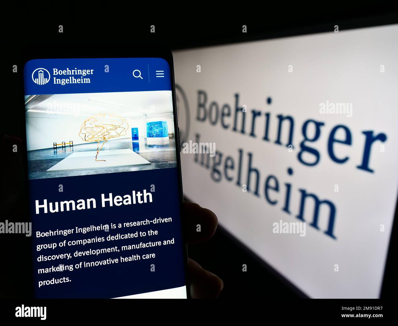 Persona che tiene in mano smartphone con pagina web della società farmaceutica Boehringer Ingelheim sullo schermo con logo. Messa a fuoco al centro del display del telefono. Foto Stock