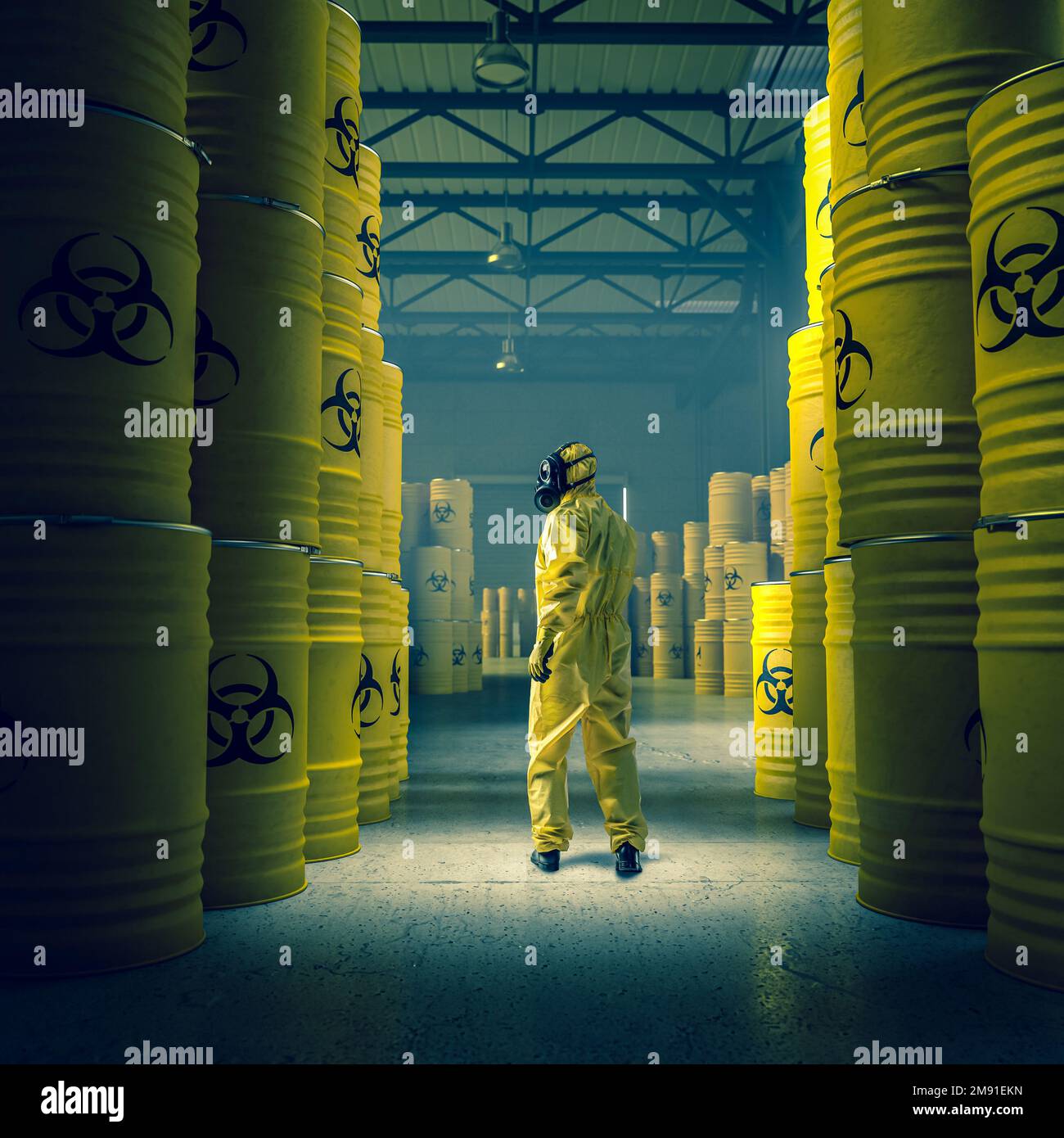 uomo in tuta di protezione gialla in magazzino con fusti metallici con residui radioattivi e chimici. Foto Stock