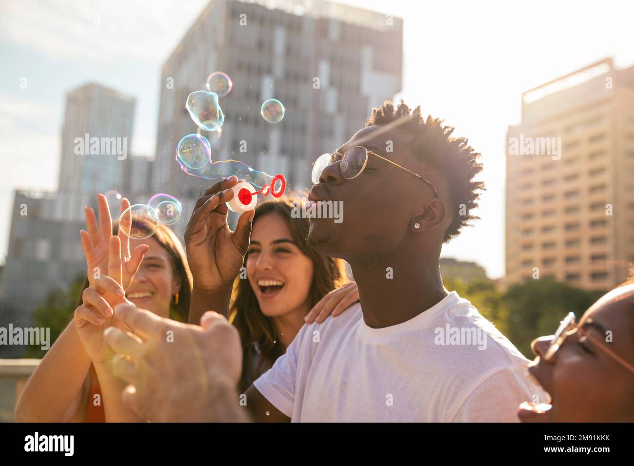Gruppo di amici multirazziali felici divertirsi con le bolle di sapone in città - giovani amici allegri sorridenti con le bolle il giorno di sole - felicità Foto Stock