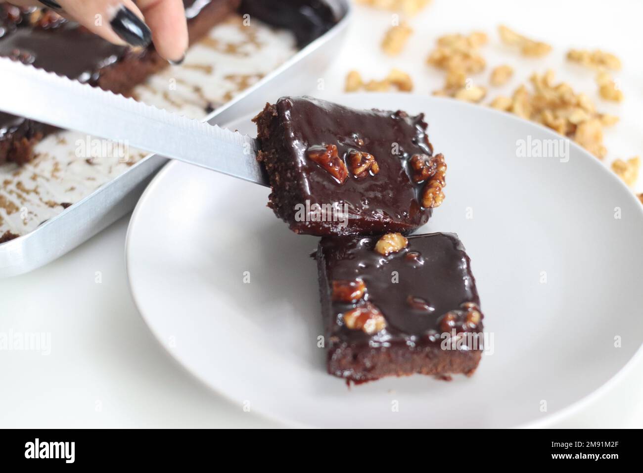 Fetta di Texas Sheet Cake servita su un piatto. Si tratta di una grande e sottile torta al cioccolato sormontata da una ricca glassa di noce al cioccolato. È umido e soffice, w Foto Stock